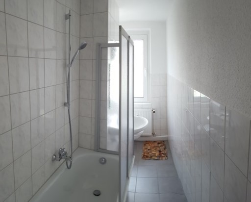 Badezimmer der Ferienwohnung mit Badewanne und Duschabtrennung