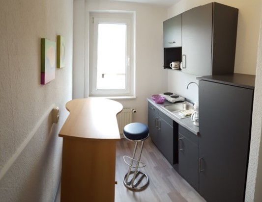 Küche der Ferienwohnung mit Küchenzeile, Tisch und Sitzplätzen